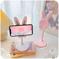 Phone holder with bunny ears on a desk next to a book