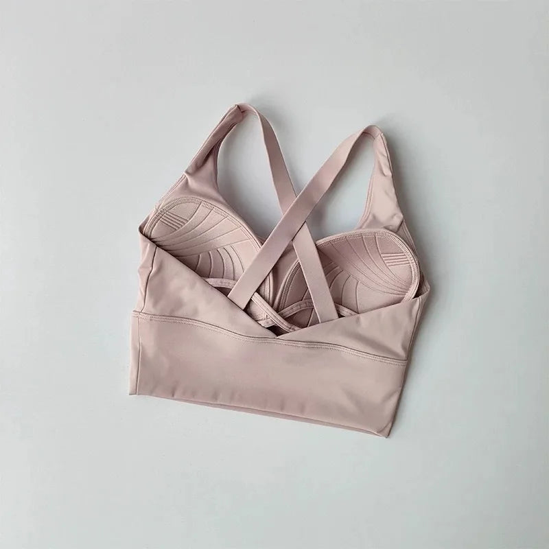 Pink sports bra with criss-cross straps on a light gray background