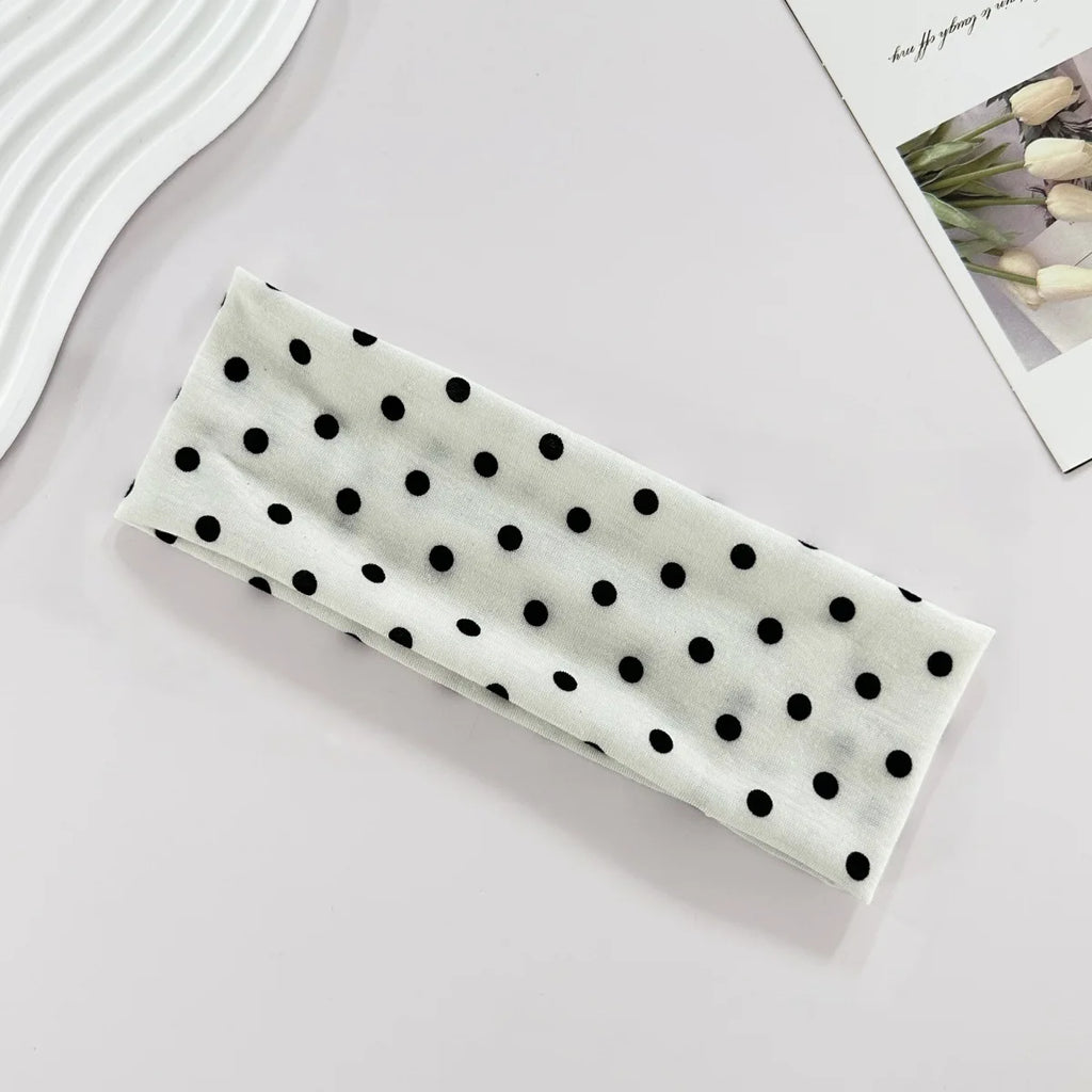 Rectangular white object with black polka dots on a light gray surface