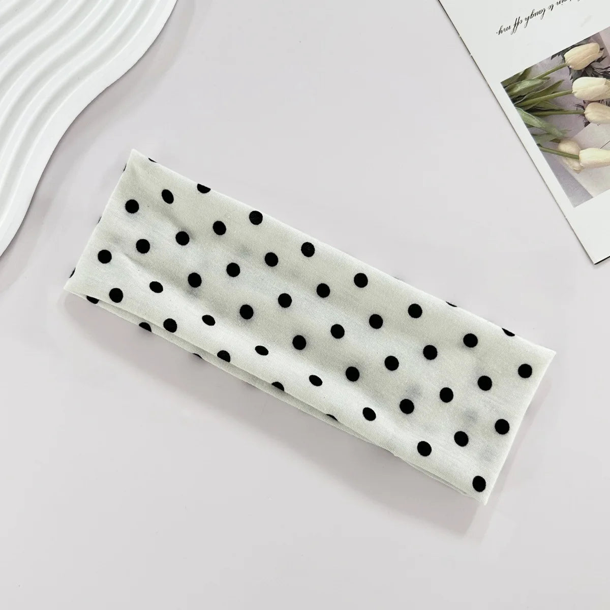 Rectangular white object with black polka dots on a light gray surface