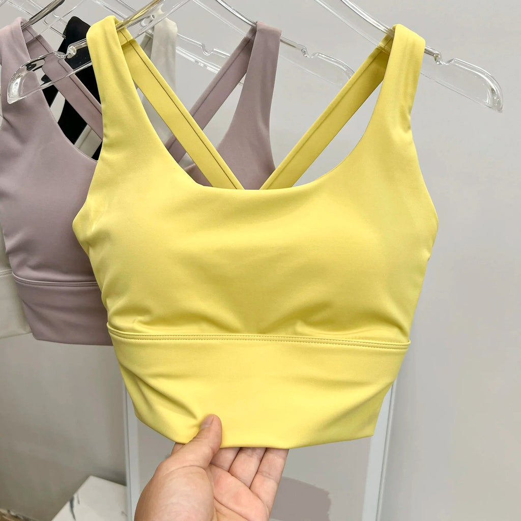 Yellow crop top held by a hand with a gray background