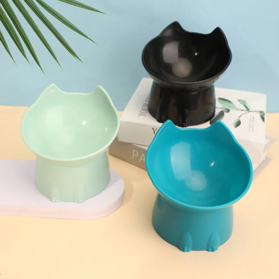 Three colorful cat-shaped bowls on a light blue and beige background