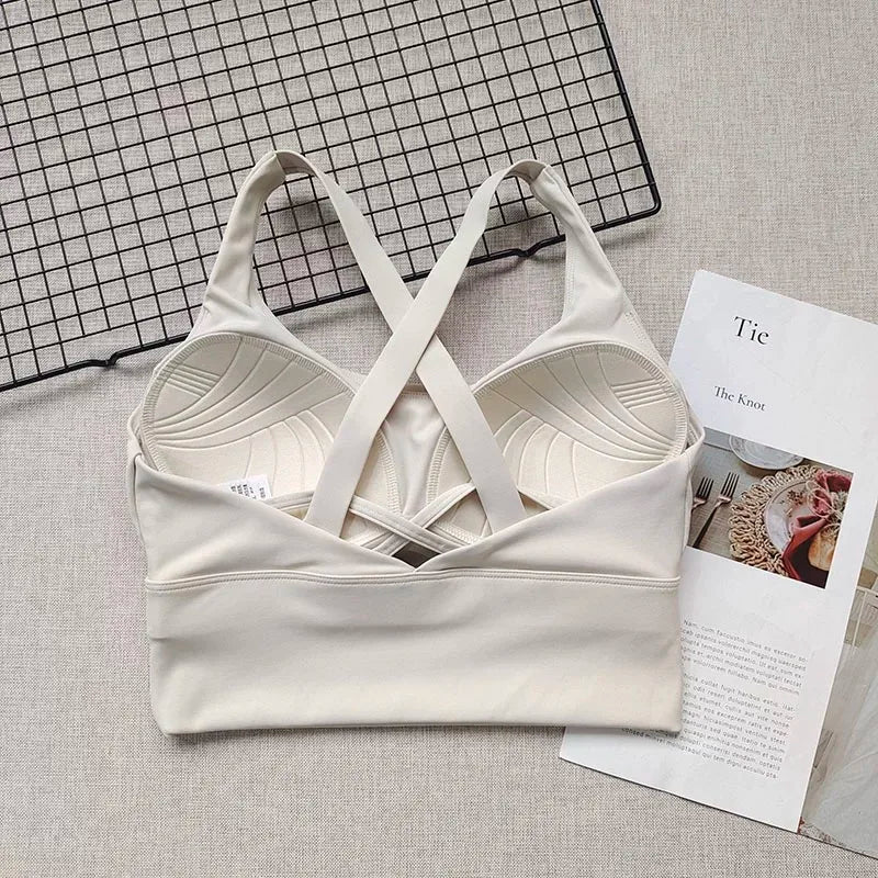 White bralette with criss-cross straps on a textured surface with a magazine underneath.