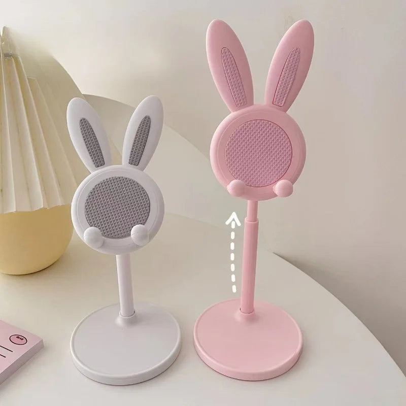 Two microphone stands with bunny ears, one pink and one white, on a light surface.