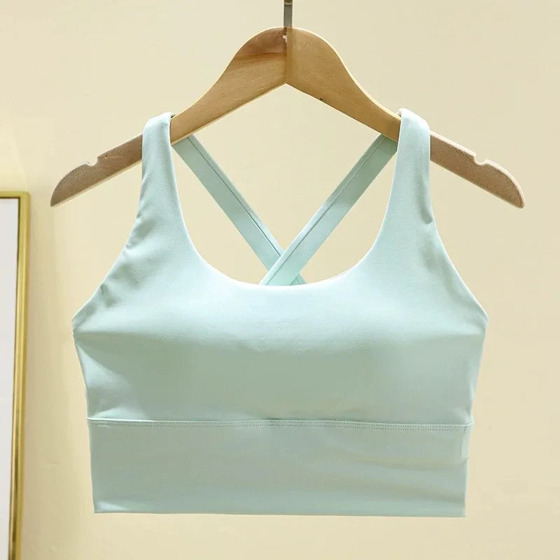 Light blue sports bra on a wooden hanger against a beige background