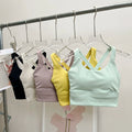 Set of colorful sports bras hanging on a rack against a neutral background