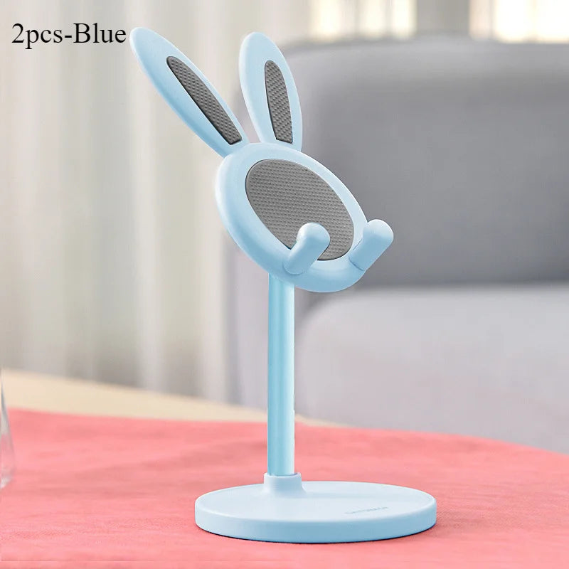 Blue bunny-shaped phone stand on a pink surface with a blurred background