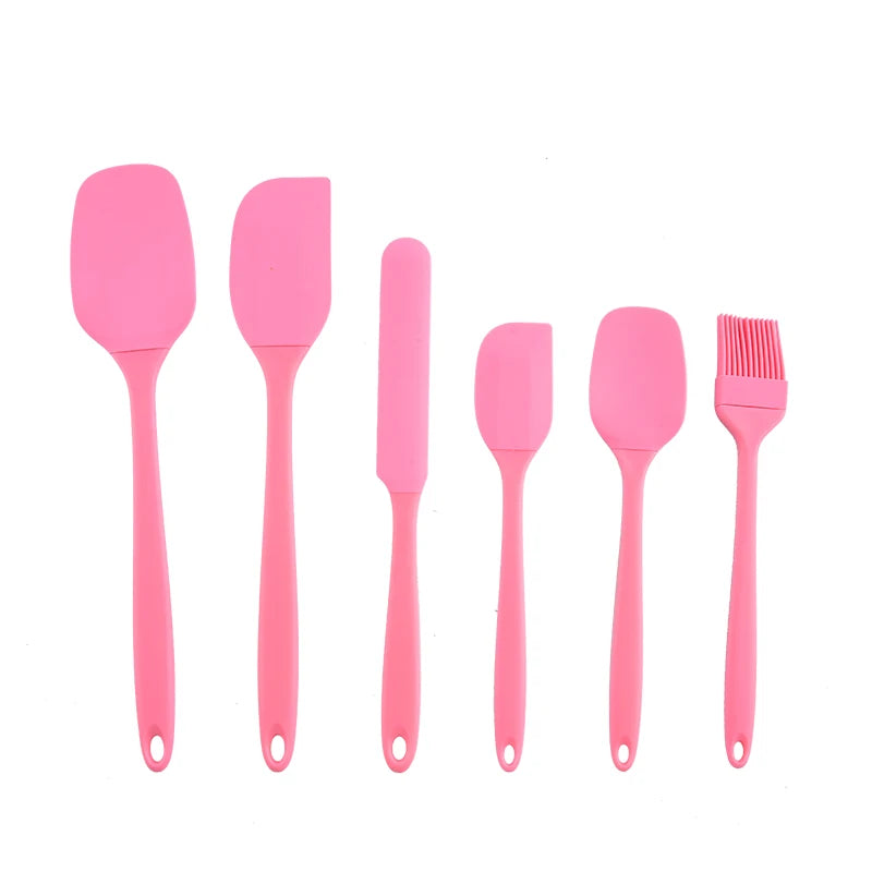 Set of pink silicone kitchen utensils on a white background
