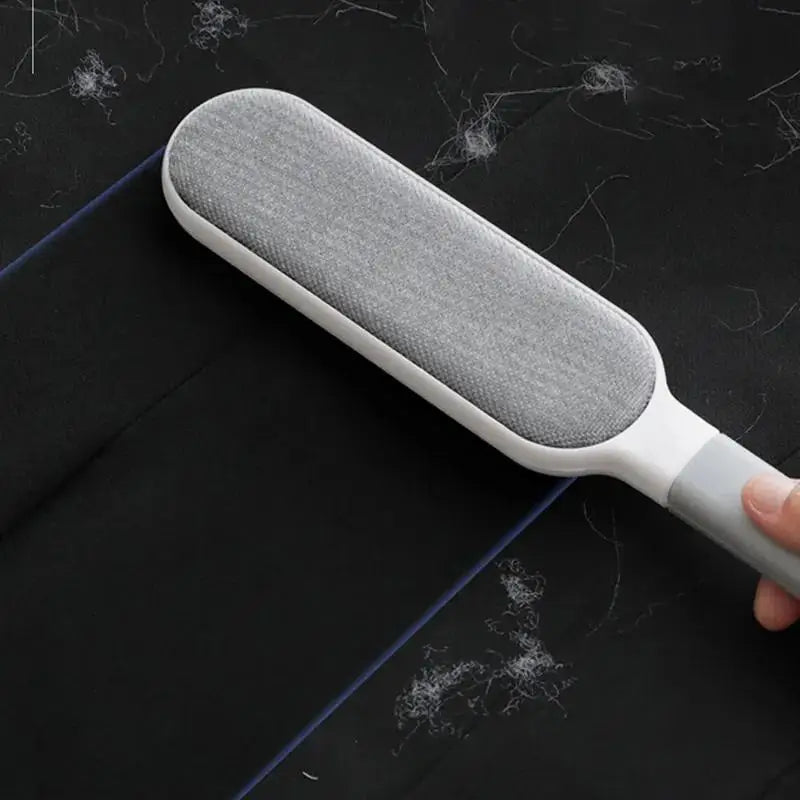 Gray and white lint roller being used on a dark surface with hair and dust.