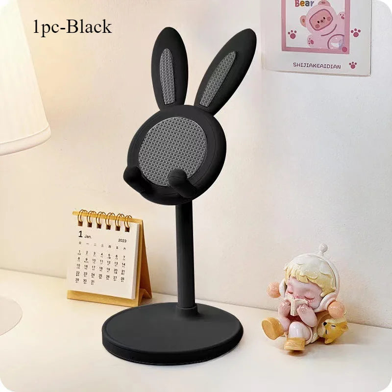 Black rabbit-shaped microphone stand on a desk with a calendar and decorative item in the background.