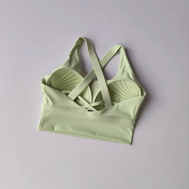 Light green sports bra with criss-cross straps on a gray background