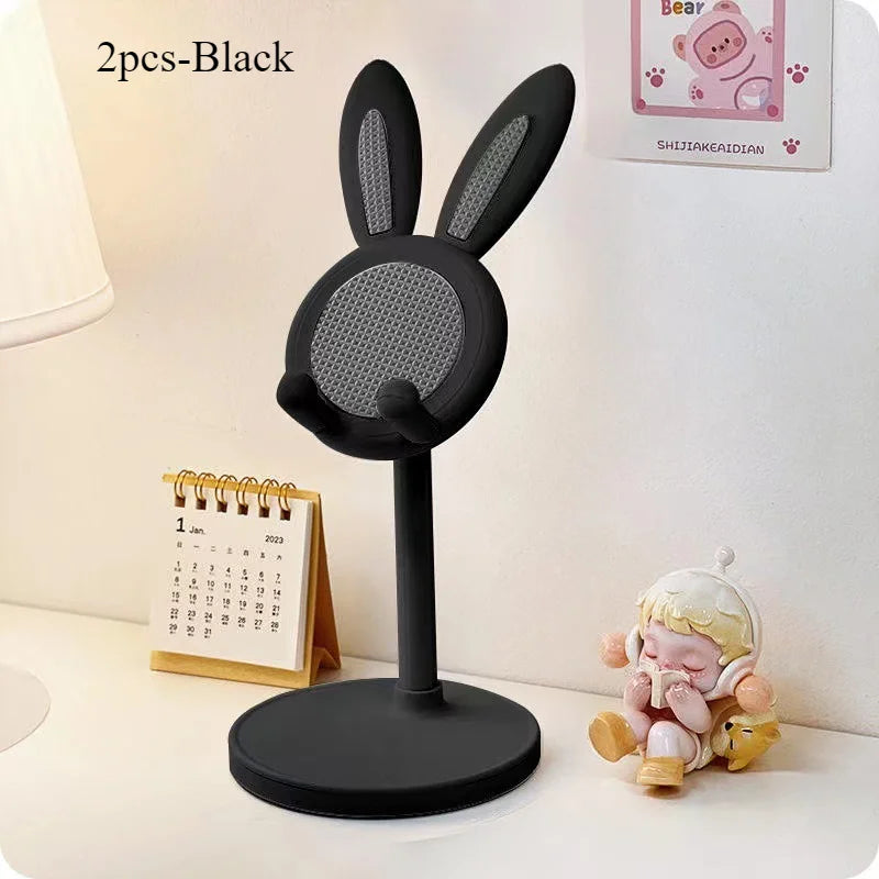 Black rabbit-shaped microphone stand on a desk with a calendar and decorative item in the background.