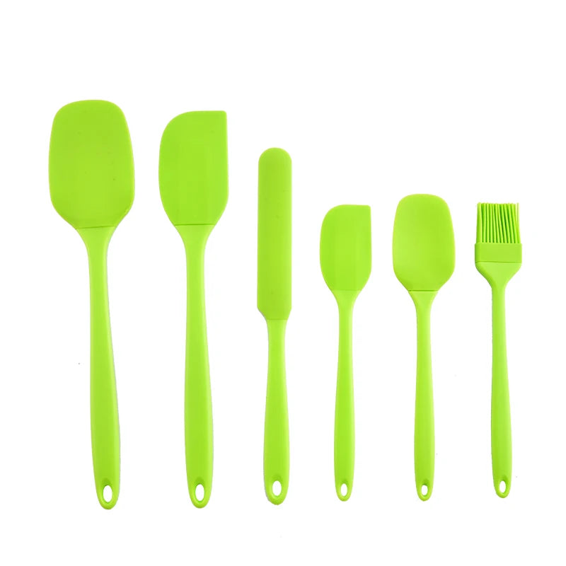 Set of green silicone kitchen utensils on a white background
