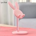 Pink bunny-shaped phone stand on a pink surface with a blurred background