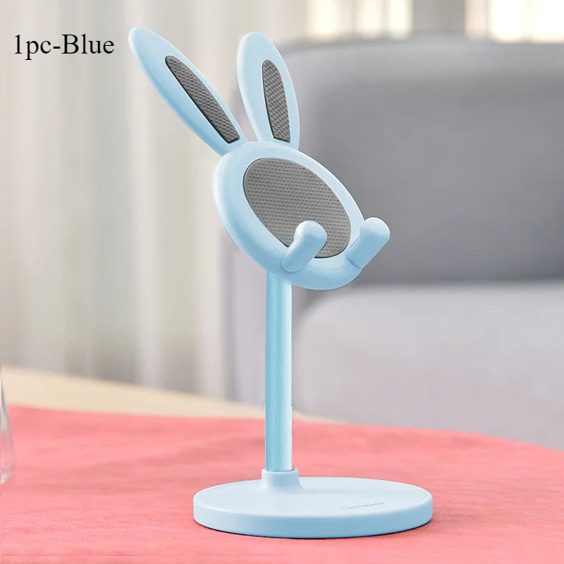 Blue bunny-shaped phone stand on a pink surface with a blurred background