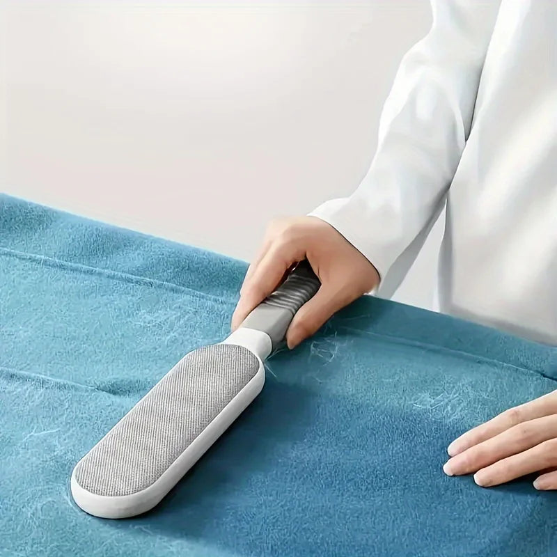 Person using a gray brush to remove pet hair from a blue surface